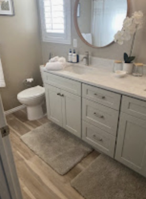 Clean bathroom with a round mirror and gray vanity